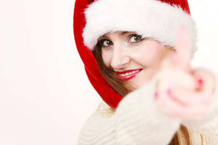 Christmas time. Young latin woman wearing santa claus hat pointing at you with finger. Studio shot.の写真素材