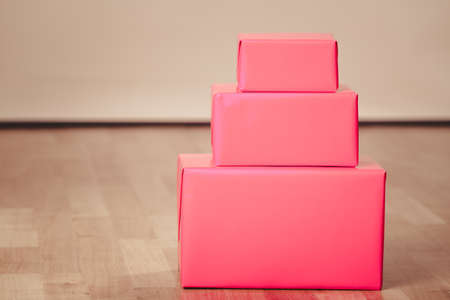 Helping and giving concept. Three red gifts boxes present lying on floor panels indoor.