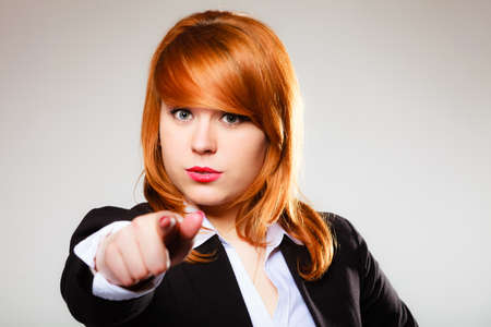Business woman point finger at you looking at camera on gray backgroundの写真素材