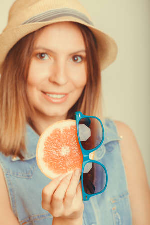 Happy glad woman tourist in straw hat holding grapefruit citrus fruit and sunglasses. Healthy diet food. Summer vacation holidays concept.  の写真素材