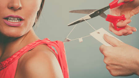woman girl removing cutting label board price tag off new dress cloth with scissors. female after shopping.の写真素材