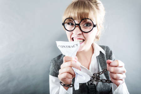 Business and stress concept. Furious businesswoman in glasses with chained hands holding contract grunge background unusual angle viewの写真素材