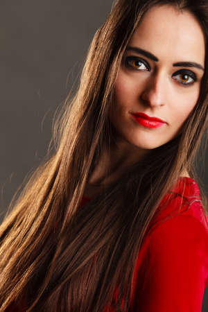 Closeup portrait beautiful young woman long straight hair dark makeup red lips on grayの写真素材