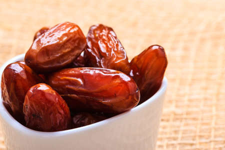 Healthy eating. Dried dates in white bowl on table cloth rustic background