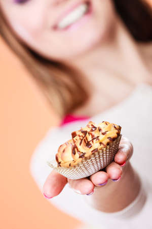 Delicious tasty sweet cake cupcake in human hand. Gluttony concept.の写真素材