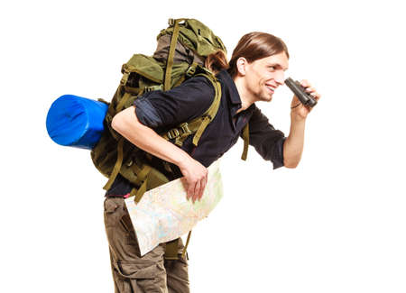 Man tourist backpacker holding map looking through binoculars. Young guy hiker backpacking. Summer vacation travel. Isolated on white background.の写真素材