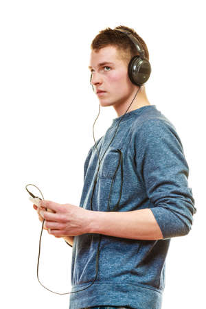 Teenage and technology concept. Young man casual style with headphones smartphone listening music isolated on whiteの写真素材