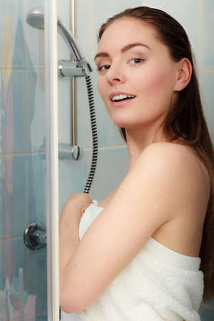Girl showering in shower cabin cubicle enclosure. Young woman with white towel taking care of hygiene in bathroom.の写真素材