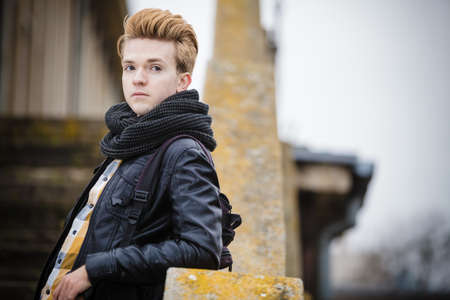 Fashionable handsome man model posing outdoors on staircase in autumal cold day. Street fashionの写真素材