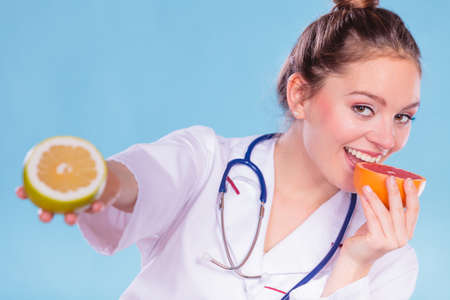 Happy dietitian nutritionist holding grapefruit having fun. Woman promoting healthy food fruit. Right eating nutrition and slimming concept.の写真素材