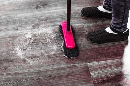 Cleanup housework concept. Closeup broom and female foots. Cleaning woman sweeping wooden floor.の写真素材