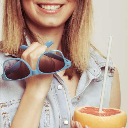 Happy glad woman tourist holding sunglasses and grapefruit citrus fruit. Seductive and flirty girl. Healthy diet food. Summer vacation holidays concept.の写真素材
