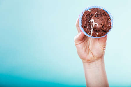 Delicious tasty sweet chocolate muffin in human hands. Confectionery food.の写真素材