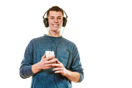 Teenage and technology concept. Young man casual style with headphones smartphone listening music...