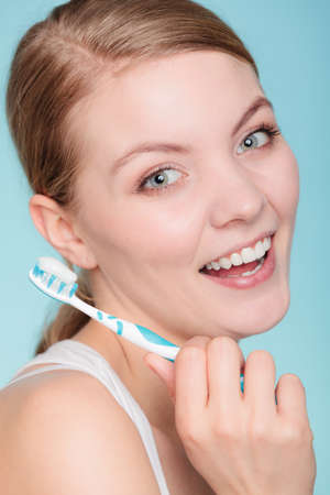 Young woman brushing cleaning teeth. Girl holds toothbrush with toothpaste on it. Oral hygiene.