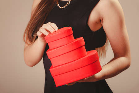 Valentine day. Woman in black holding three hearts boxes gifts presents. Part body of elegant model with valentines symbol sign. Studio shot.の写真素材