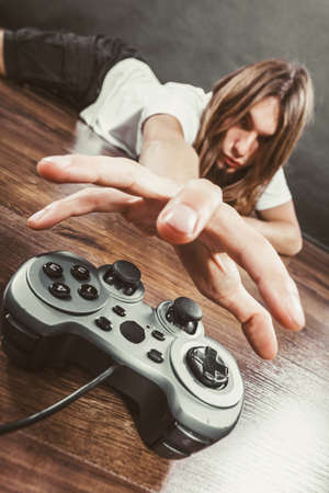 Addiction and dependency concept. Young man with pad joystick playing games. Male addicted to console videogames.の写真素材