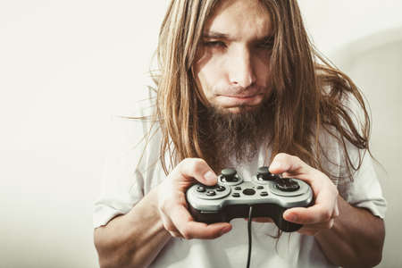 Lifestyle of young people. Student man spending time on playing games videogames console. Long haired guy focus on gaming.の写真素材