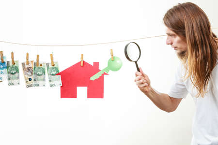 Concept of real estate and deal. Seller man with house model and banknotes. Selling and buying proposition.の写真素材