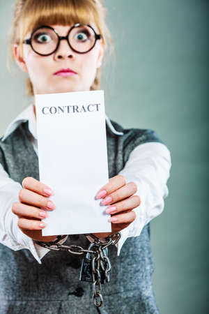 Business concept. Serious businesswoman with chained hands holding contractの写真素材