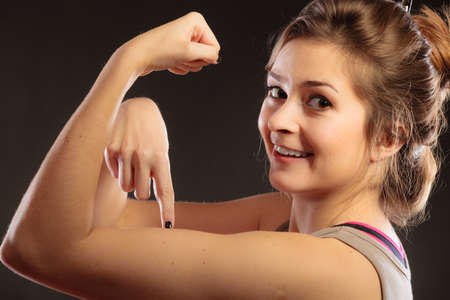 strength and power concept. Young woman teen girl showing her muscles on blackの写真素材