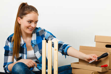 Woman moving into new apartment house assembling furniture. Young girl arranging interior and unpacking boxes.の写真素材