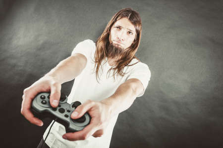 Lifestyle of young people. Student man spending time on playing games videogames console  . Long haired guy focus on gaming.の写真素材
