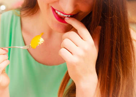 Woman eating delicious gourmet sweet cream cake cupcake with fruits. Glutton girl having breakfast...