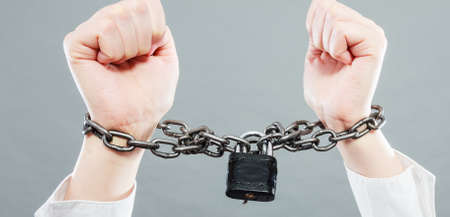Crime, arrest jail or business concept. Closeup woman with chained hands on grunge background