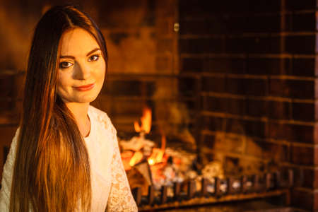 Woman relaxing resting at fireplace. Young girl heating warming up. Winter at home.の写真素材