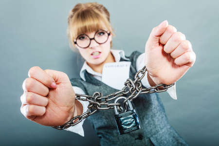 Business concept. Serious businesswoman with chained hands holding contractの写真素材