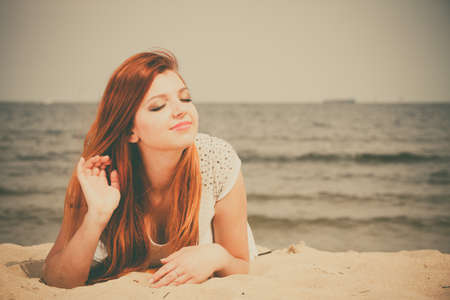Holidays, vacation travel and freedom concept. Attractive red haired girl on beach. Young pretty woman relaxing on the sea coast.の写真素材