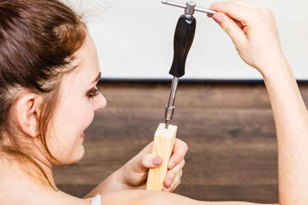 Woman assembling wooden furniture using screwdriver. DIY enthusiast. Young girl doing home improvement.の写真素材