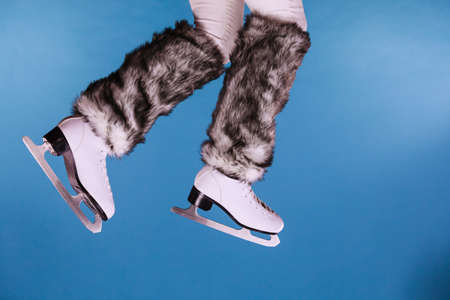 Woman legs wearing skates fur warm socks. Girl getting ready for ice skating. Winter sport activity. Studio shot on blueの写真素材