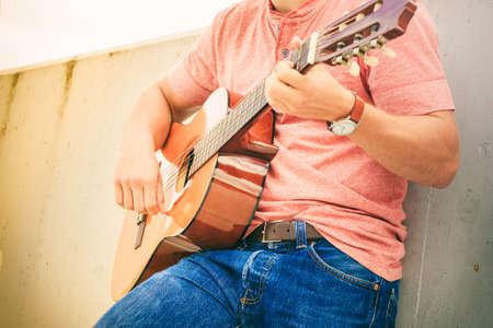 Performance and show on fresh air. Part body of young fashionable man playing classic guitar...