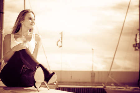 Resting and relaxation. Young beauty woman relaxing on marina on fresh air. Fashionable blondie girl spending time outdoor.の写真素材
