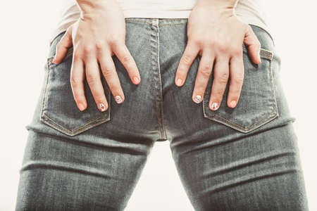 Closeup of human with hands palms on buttocks ass in jeans trousers.