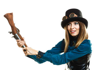 Young steampunk islolated girl on white playing with fancy rifle. Fantasy old fashion wearing hat and goggle.の写真素材