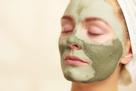 Skin care. Woman face with green clay mud mask close up. Girl taking care of oily complexion. Beauty treatment.の写真素材