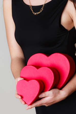 Happiness, valentines day and love concept. elegant woman in black dress with red heart-shaped gift...
