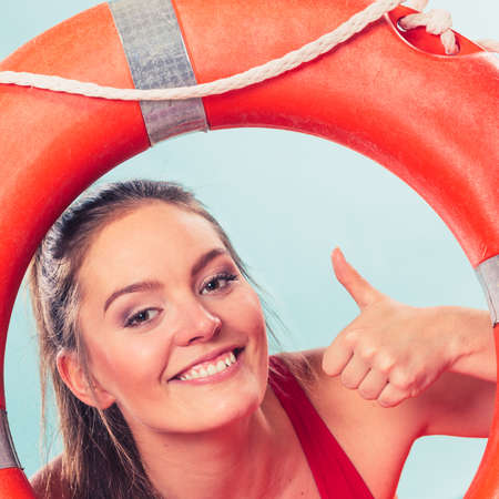 Happy lifeguard with ring buoy lifebuoy. Woman girl supervising swimming pool water giving thumb up. Accident prevention.の写真素材