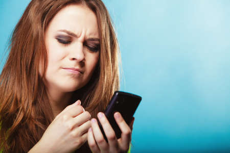 Technology and communication. Angry confused woman teenage girl texting on mobile phone, using...