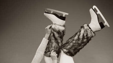 Woman legs wearing skates fur warm socks. Girl getting ready for ice skating. Winter sport activity. Studio shot b&w photoの写真素材