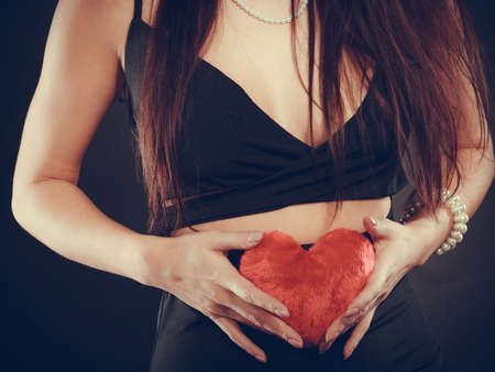 Woman long hair young female holding red heart love symbol studio shot on black. Valentines day happiness conceptの写真素材