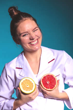 Happy dietitian nutritionist holding grapefruit having fun. Woman promoting healthy food fruit. Right eating nutrition and slimming concept.の写真素材