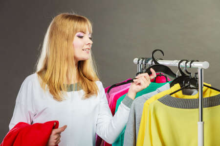 Pretty happy woman watching clothing from new collection wardrobe. Young undecided shopper girl choosing which clothes to wear. Shopping sale concept.の写真素材