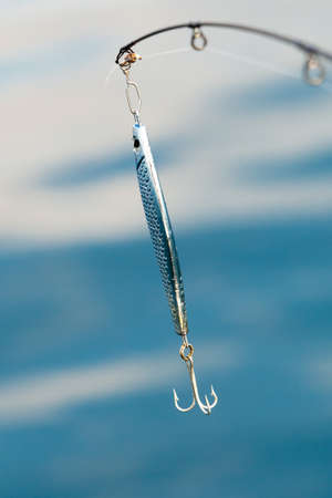 Sport and recreation. Fishing bait - rod with wobbler against the blue sea water surfaceの写真素材