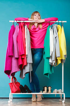 Happy smiling pretty woman choosing clothes to wear in wardrobe. Gorgeous young girl customer shopping in mall shop. Fashion clothing sale concept.の写真素材