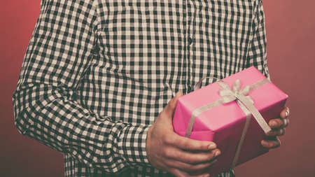 People celebrating xmas love and happiness concept - young man holding present pink gift box in handsの写真素材