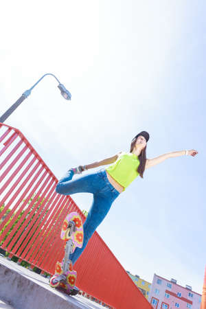 Summer sport and active lifestyle. Cool teenage girl in full length skater riding skateboard on the street. Outdoor.の写真素材